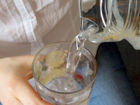 Eine Frau schenkt Leitungswasser aus einer Karaffe in ein Glas ein.