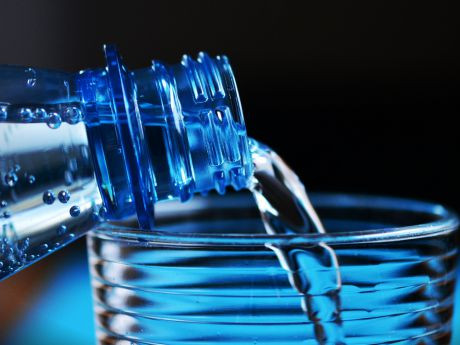 Aus einer Plastikflasche wird Wasser eingeschenkt.