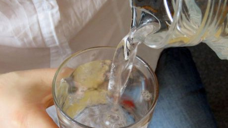 Eine Frau schenkt Leitungswasser aus einer Karaffe in ein Glas ein.