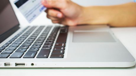 Hand mit Kreditkarte am Laptop