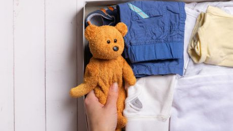 Kinderkleidung und Teddy in Schachtel