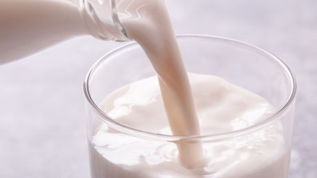 Milch wird in ein Glas eingeschenkt.